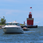 Boat cruising up the inlet of Lake Michigan with the iconic Big Red Lighthouse in the background in Holland, Michigan