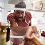 View from inside refrigerator as person reaches for groceries.