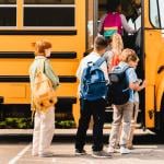 Children boarding school bus to public school.