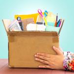 A teacher's hands holding a box of school supplies.