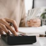 A woman budgeting using a calculator and counting money.