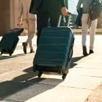 A group of three business professionals walking with their luggages for a travel.