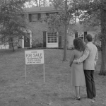 Couple standing in front of a house with a "For Sale" sign, circa 1978.