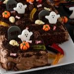 Dirt cake with chocolate cream, decorated with worms, skulls, ghosts, pumpkins, and sugar sprinkles for Halloween.