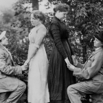 Two women dressed in suits proposing marriage to two women in unison, circa 1910. 