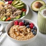 Healthy meals such as oatmeal with berries, quinoa with chicken and a glass of avocado smoothie on a table..