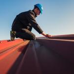 Construction worker in a helmet installing a roof.