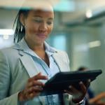 African American female consultant using touchpad while her clients are in the background in the office. 