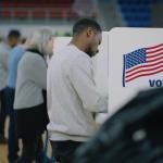 Male voter with bulletin in hands comes to a voting booth on US election day. 