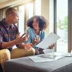 Two people discussing financial paperwork looking confused.