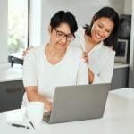 Older mother and her adult daughter looking up finance and retirement information using a laptop.