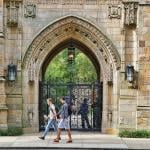 Students walk past a decorative stone archway at the entrance to Yale University in New Haven, Connecticut.