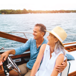 An old retired couple driving a boat on a lake at sunset