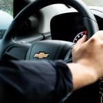 Person's hand on a Chevrolet steering wheel.