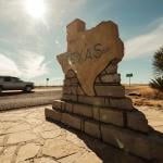 A car speeds along past a border sign for the state of Texas.