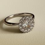 Photo of vintage platinum engagement ring with Dutch rose cut diamonds halo setting on textured beige background.