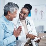 Young doctor reviewing good test results with senior patient on a tablet.