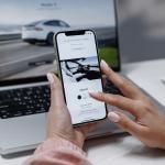 A woman is researching an EV using a laptop and phone.