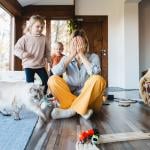 Stressed out mother sitting on the floor while kids are playing around.