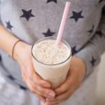 A woman holding a glass of blended oats drink. Oatzempic is one of the viral weight loss hack trends of the past year.