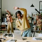 A group of happy ethnically diverse Gen Z coworkers doing morning exercise in a modern office. 