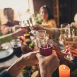 Adults in a family clinking glasses of champagne/wine during a celebration around a table.