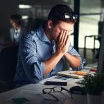 A male employee experiencing strain and stress and working late nights at his office.