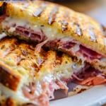 A reuben sandwich that's been grilled with Swiss cheese, sauerkraut, mustard, and corned beef. 