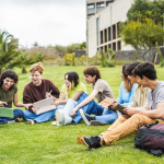 A group of students studying together on the lawns of a college campus