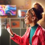 Woman using phone with mounted in a ring light to create content in a home studio setting.