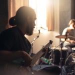 Band members such as a guitarist and drummer during a rehearsal.