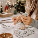 Woman organizing expenses with holiday purchases and ornaments still around her.