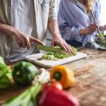 A couple preparing leafy green salad meals in the kitchen.