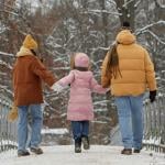 Back view of young family with child walking on bridge together in a small town.