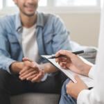 Psychologist takes notes while talking to patient.