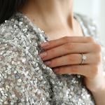 A woman is wearing a silver sequin top to match her engagement ring.