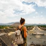 A female American tourist with a backpack enjoys the view from the top of the Moon Pyramid in Teotihuacan, Mexico.