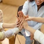 A group of children and a psychologist doing a high-five for great teamwork.