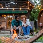 A multiracial couple having quality time by a campfire outdoors.