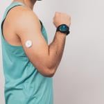 A fit young man monitors blood sugar with a glucose patch and a smartwatch.