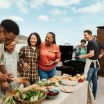 A multigenerational family bonds over food and happily engaging during a summer outdoor gathering.