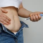 A woman injecting her stomach with an Ozempic (semaglutide) pen.