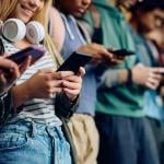 A group of high school students texting using their phones.