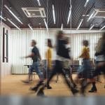 Photo of motion-blurred employees walking in front of office conference room.