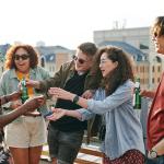A group of young adults hanging out at a rooftop outdoor party.