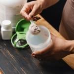 A spoonful of creatine powder being put into a shaker.