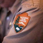 A closeup on the sleeve patch of a ranger's uniform showing the National Park Service logo.