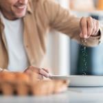 A man seasoning egg mixture with plenty of salt.