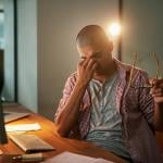 Stressed out man in front of his computer massaging forehead.