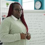 A black female teacher holding lessons in mathematics in a classroom.
